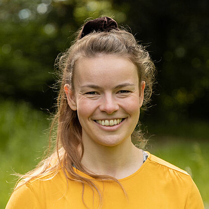 Mitarbeiterfoto vor grünem Hintergrund draußen