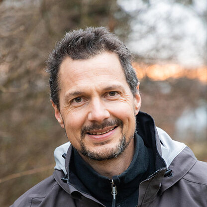 Mitarbeiterfoto vor grünem Hintergrund draußen