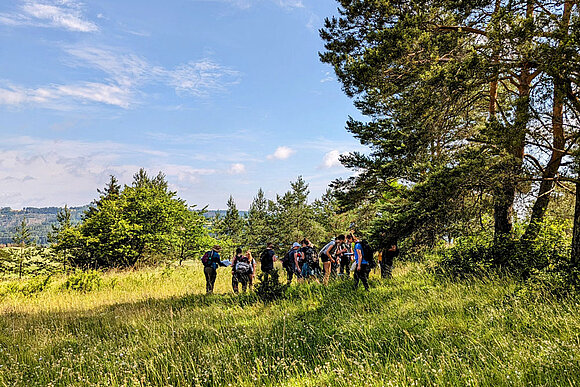 Eine Gruppe von Kursteilnehmern steht draußen in der Natur. 